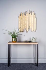 Console table with decorative items against a light gray wall with a modern mirror.