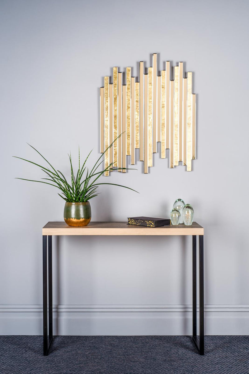 Console table with decorative items against a light gray wall with a modern mirror.