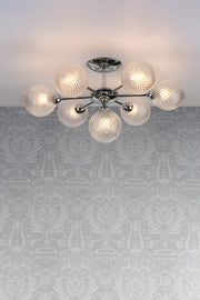 Modern ceiling light fixture with glass shades on a patterned wall.