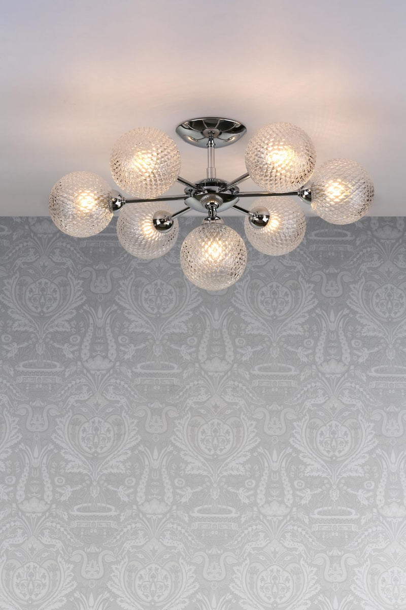Modern ceiling light fixture with glass shades on a patterned wall.