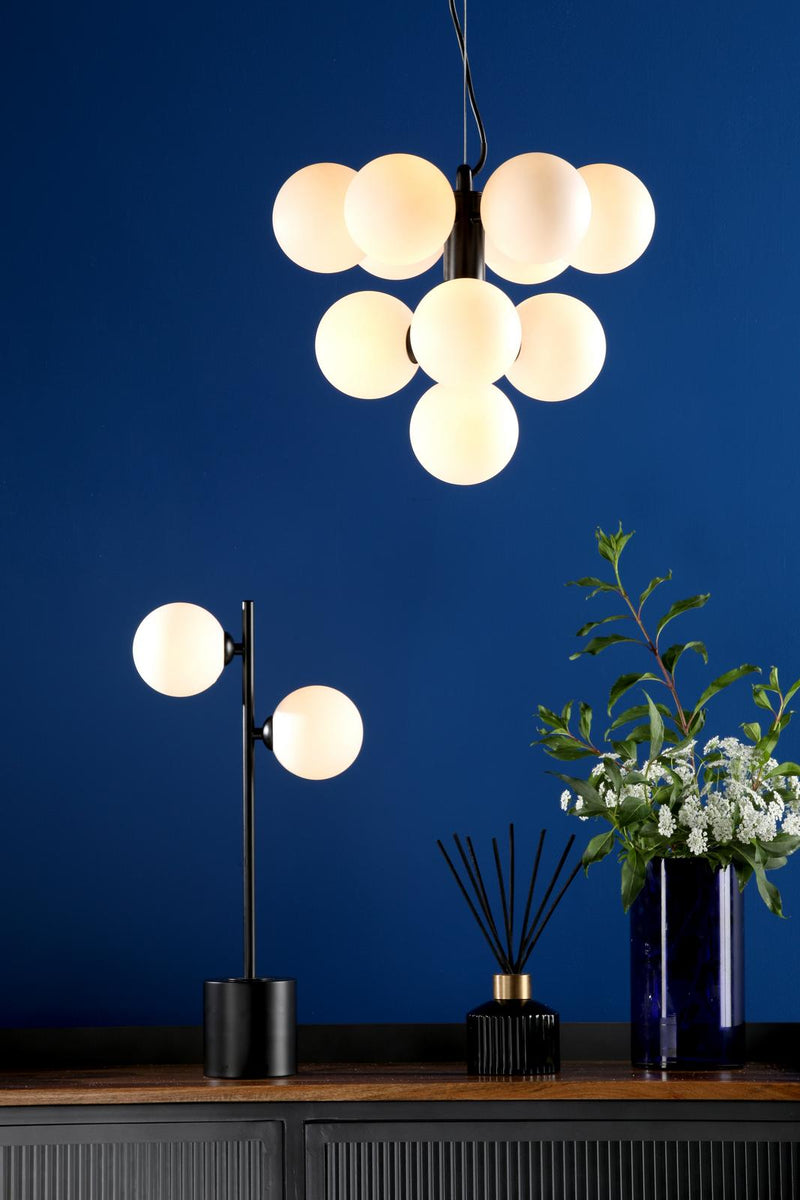 Modern chandelier and table lamp on a wooden surface with a blue wall background