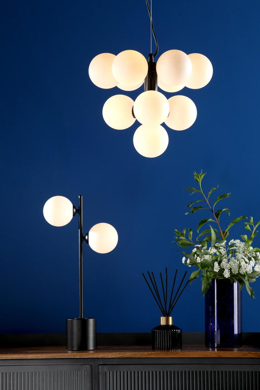 Modern chandelier and table lamp on a wooden surface with a blue wall background